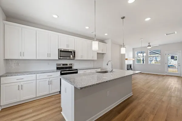 a kitchen with stainless steel appliances granite countertop a sink dishwasher a stove and a refrigerator with wooden floor