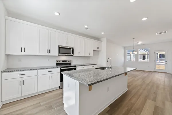 a kitchen with granite countertop white cabinets and stainless steel appliances