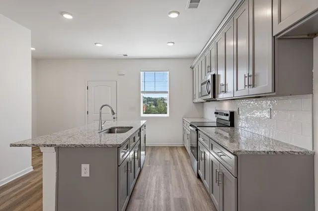 a kitchen with stainless steel appliances granite countertop a sink stove and cabinets