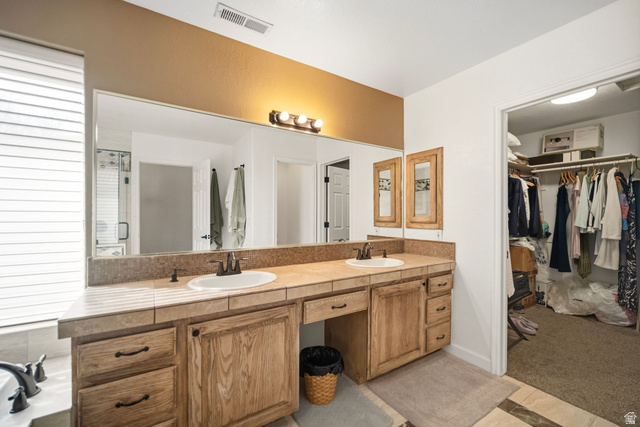 1985 West Rivers Edge Lane St. George, UT 84770 - Photo 24 of 42 Bathroom featuring double vanity, a walk in closet, light colored carpet, a bath, and light tile patterned flooring