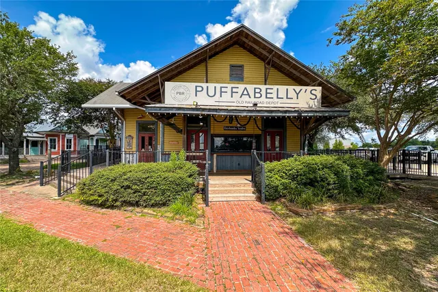 a front view of a building with a garden and trees