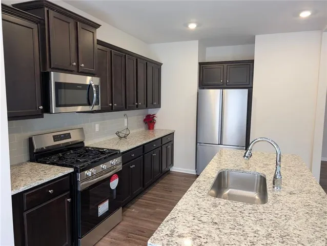 a kitchen with stainless steel appliances granite countertop a stove a sink and a microwave