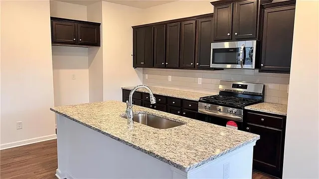 a kitchen with stainless steel appliances granite countertop a sink stove and microwave