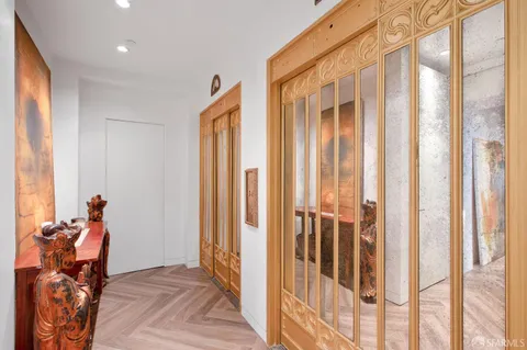a view of a hallway with wooden floor and a bathroom
