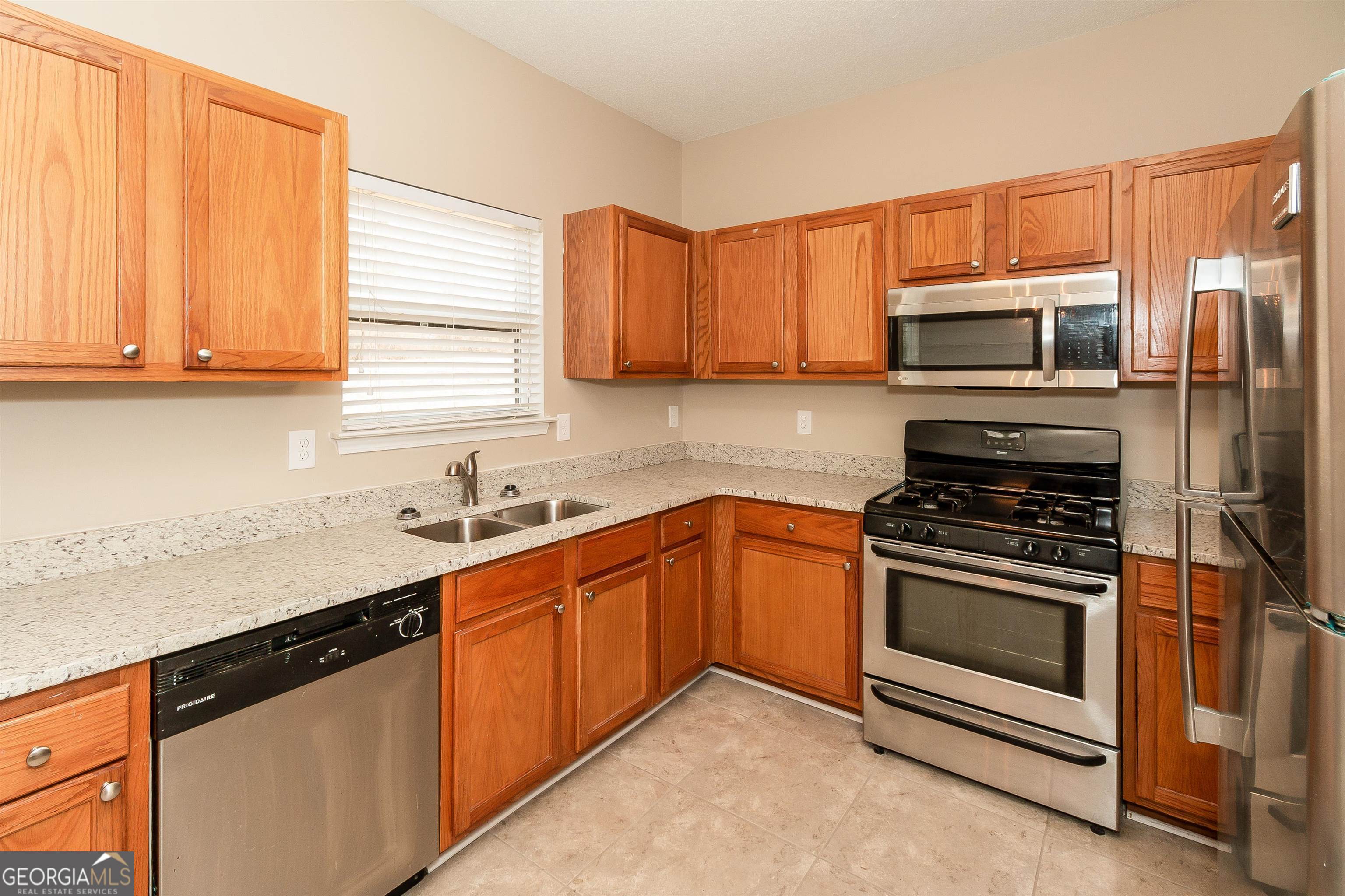 2413 Hackamore Drive Atlanta, GA 30349 - Photo 11 of 15 a kitchen with stainless steel appliances granite countertop a stove microwave and sink