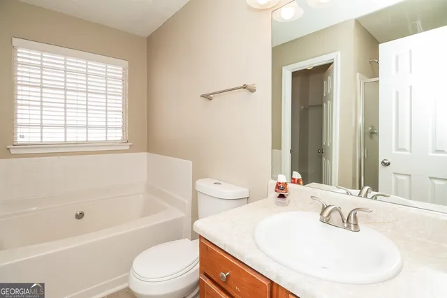 a bathroom with a bathtub sink vanity mirror and toilet