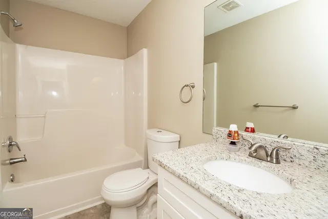 a bathroom with a granite countertop sink a toilet and a bathtub