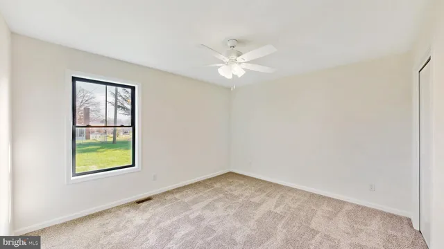 an empty room with windows and ceiling fan