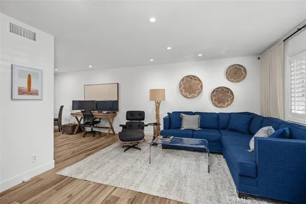 a living room with couches a computer on a desk and chair with wooden floor
