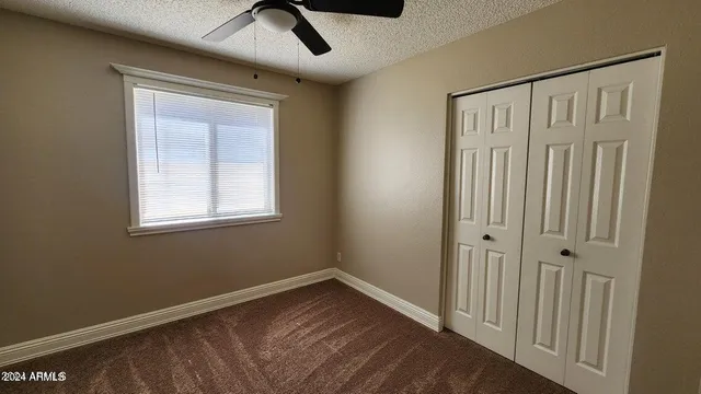 an empty room with windows and fan
