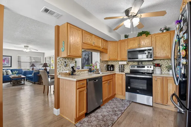 a kitchen with granite countertop a stove top oven a sink dishwasher a dining table and chairs with wooden floor