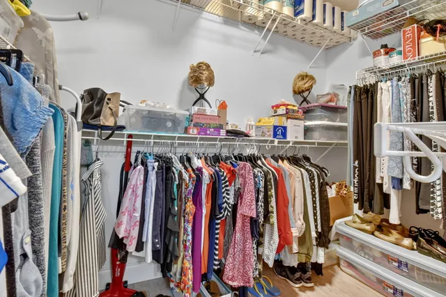 a view of walk in closet with clothes and shoes
