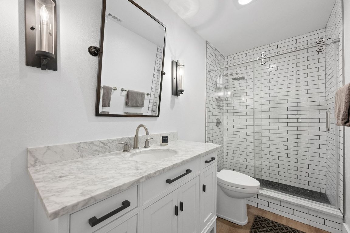 1709 Channel Road Austin, TX 78746 - Photo 23 of 27 a bathroom with a granite countertop toilet sink and mirror