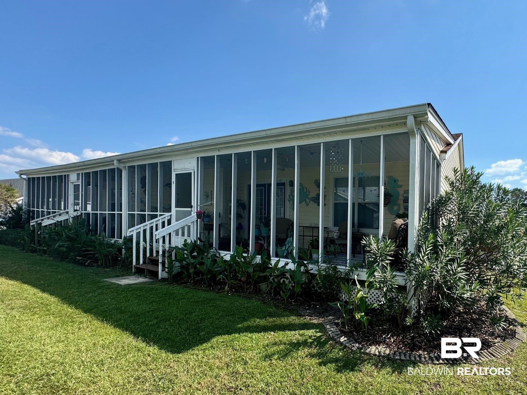 3200 Loop Road, Unit 55 Orange Beach, AL 36561 - Photo 33 of 40 Back of property with a sunroom and a lawn