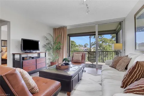 a living room with furniture a flat screen tv and floor to ceiling window