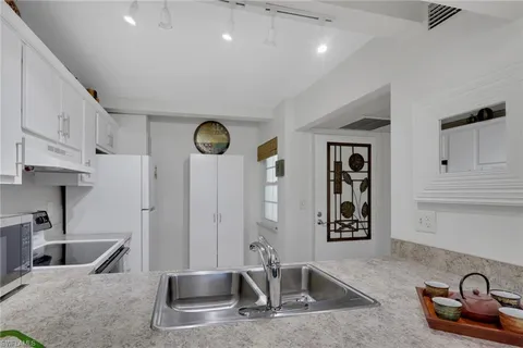 a kitchen with stainless steel appliances granite countertop a sink a stove and a refrigerator with wooden floor