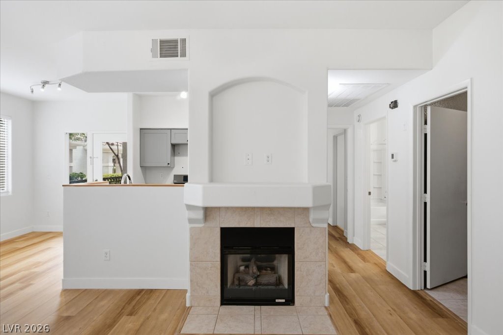 9050 West Warm Springs Road, Unit 1033 Las Vegas, NV 89148 - Photo 17 of 26 A centrally placed fireplace with an arched alcove anchors this welcoming living area, featuring rich hardwood floors.