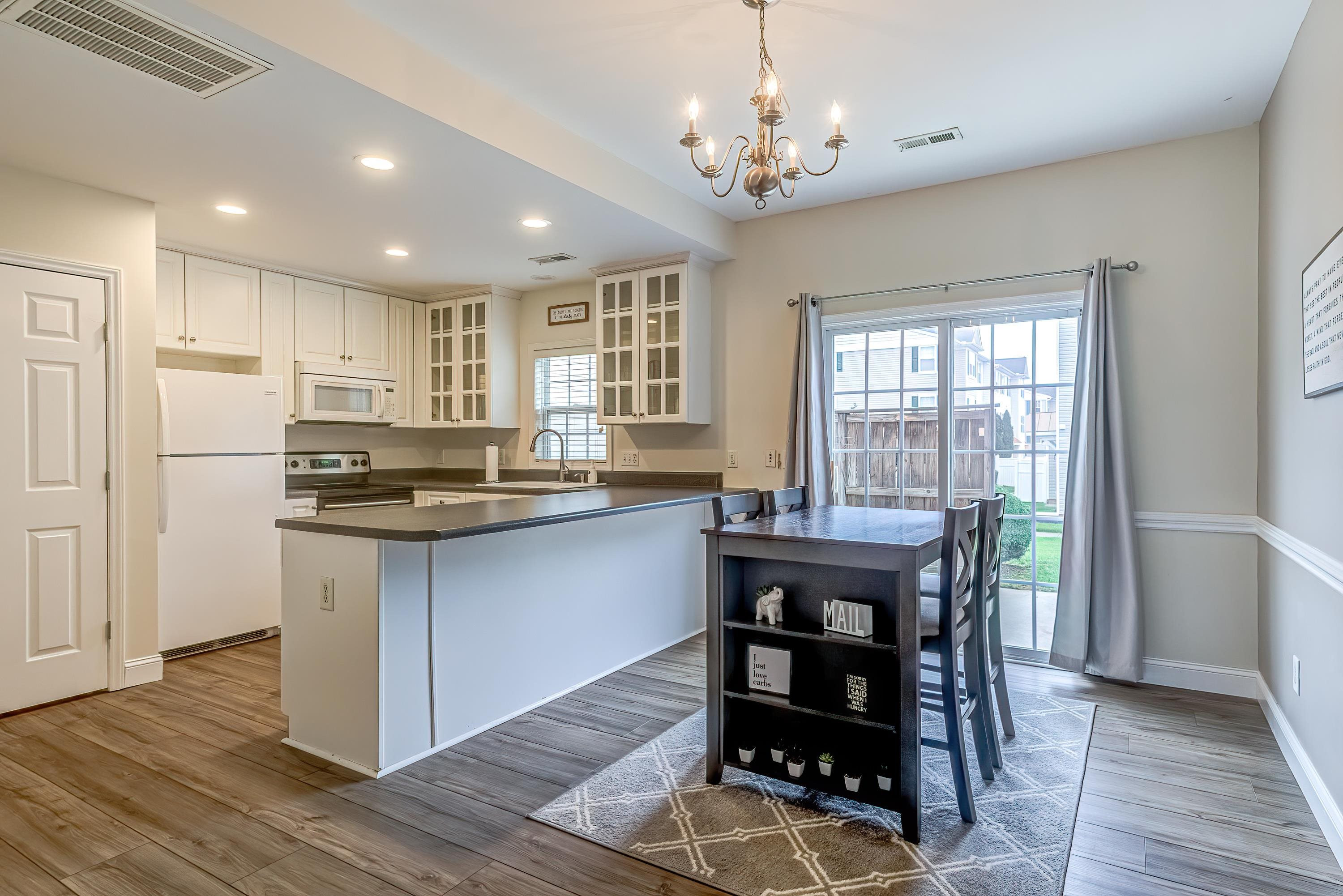 2131 Piney Brook Road, Unit 104 Raleigh, NC 27614 - Photo 11 of 37 a kitchen with stainless steel appliances granite countertop a stove a refrigerator a sink dishwasher a dining table and chairs with wooden floor
