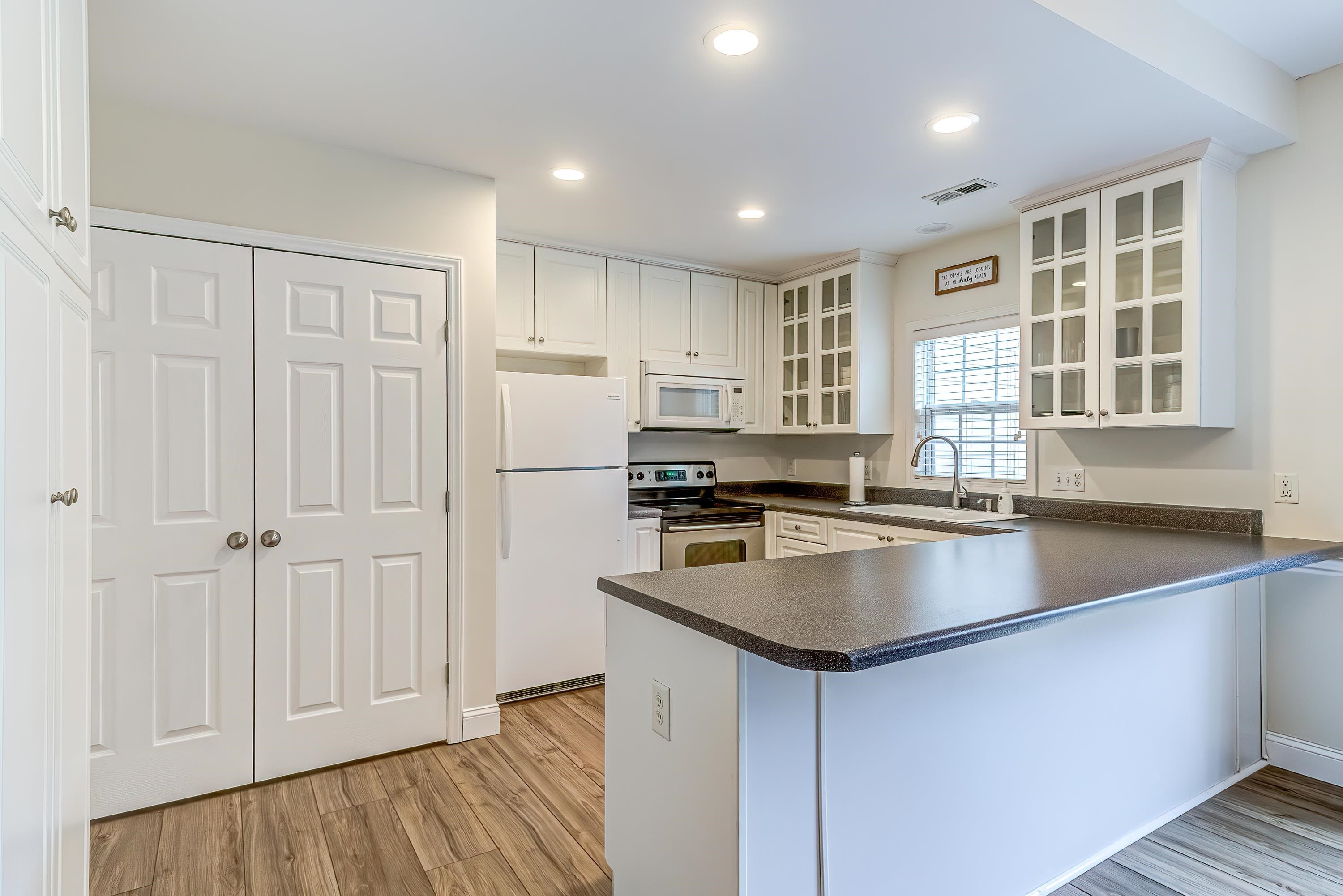 2131 Piney Brook Road, Unit 104 Raleigh, NC 27614 - Photo 14 of 37 a kitchen with stainless steel appliances granite countertop a refrigerator a sink dishwasher and white cabinets with wooden floor