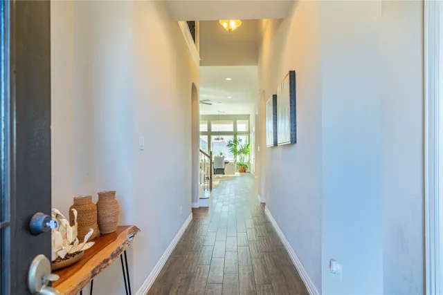a view of a hallway with wooden floor and a bathroom