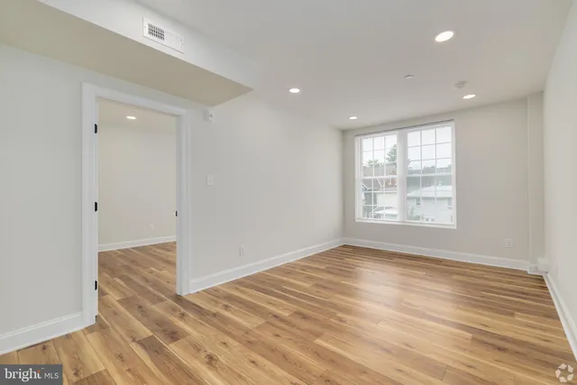 a view of an empty room with wooden floor and a window