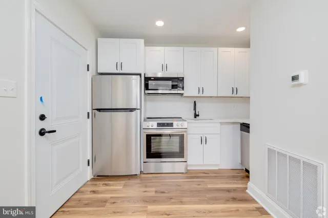 a kitchen with stainless steel appliances white cabinets and a refrigerator