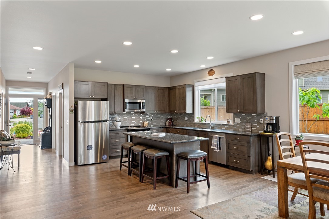 320 Blue Glacier Loop Sequim, WA 98382 - Photo 11 of 38 a kitchen with stainless steel appliances granite countertop table chairs refrigerator and sink