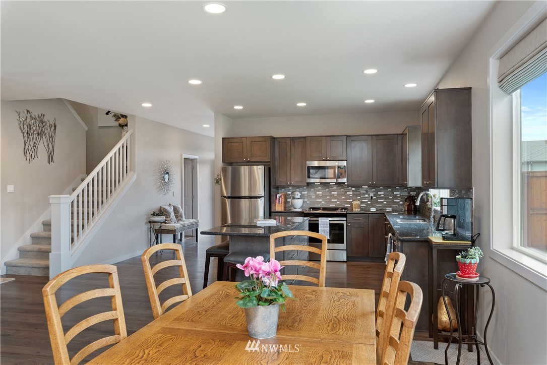 320 Blue Glacier Loop Sequim, WA 98382 - Photo 12 of 38 a kitchen with stainless steel appliances kitchen island granite countertop a refrigerator a stove top oven a dining table and chairs with wooden floor
