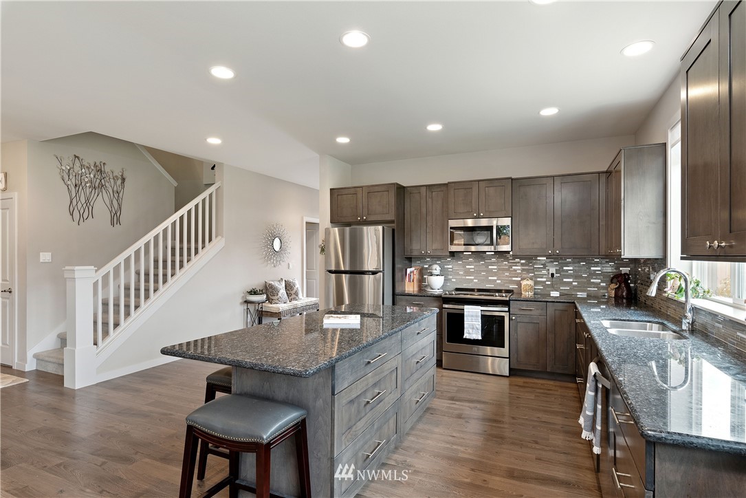 320 Blue Glacier Loop Sequim, WA 98382 - Photo 9 of 38 a kitchen with stainless steel appliances granite countertop a kitchen island hardwood floor sink stove dining table and chairs