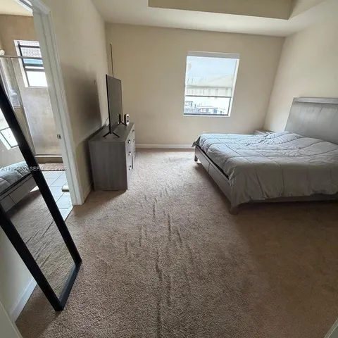 a bedroom with a bed a couch and a flat tv screen on the dresser