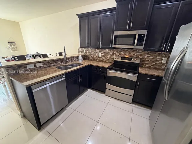 a kitchen with granite countertop a stove microwave and sink