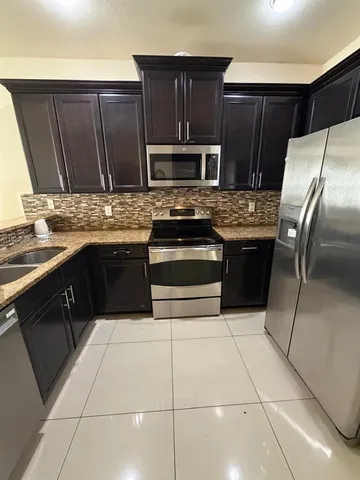 a kitchen with granite countertop a stove a sink and a refrigerator