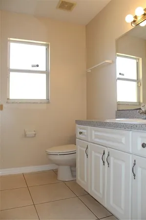 a bathroom with a toilet a sink a window and mirror