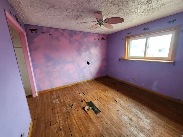 a view of a room with wooden floor and a ceiling fan