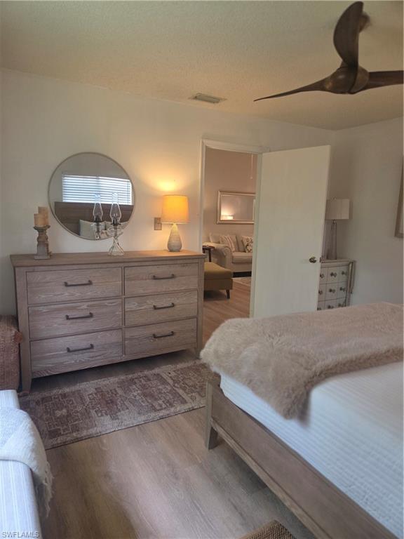 3531 County Barn Road, Unit C201 Naples, FL 34112 - Photo 13 of 20 Bedroom with ceiling fan, light wood-style flooring, and a textured ceiling
