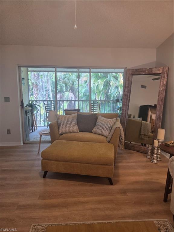 3531 County Barn Road, Unit C201 Naples, FL 34112 - Photo 6 of 20 Living room featuring wood finished floors and a textured ceiling