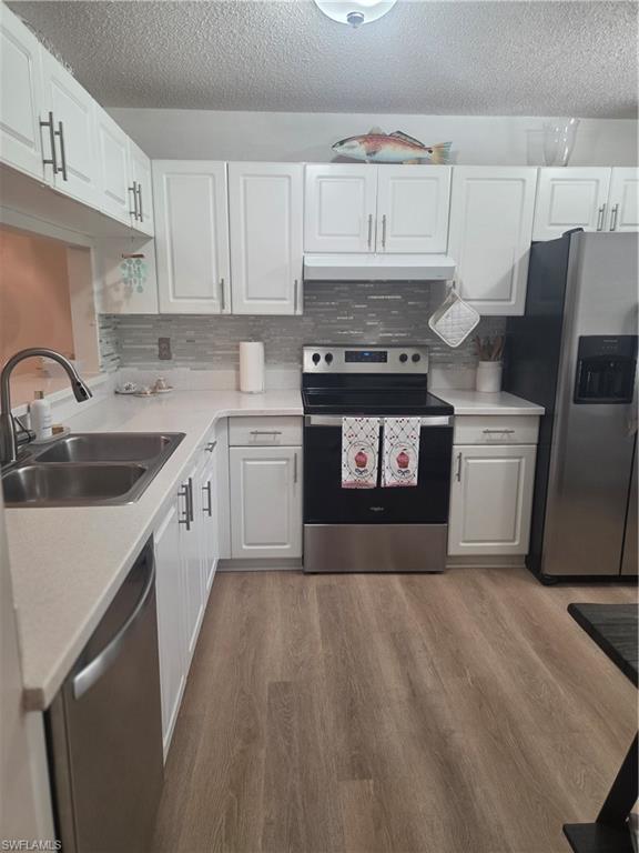 3531 County Barn Road, Unit C201 Naples, FL 34112 - Photo 8 of 20 Kitchen featuring stainless steel range with electric cooktop, white cabinets, light countertops, fridge, and a textured ceiling