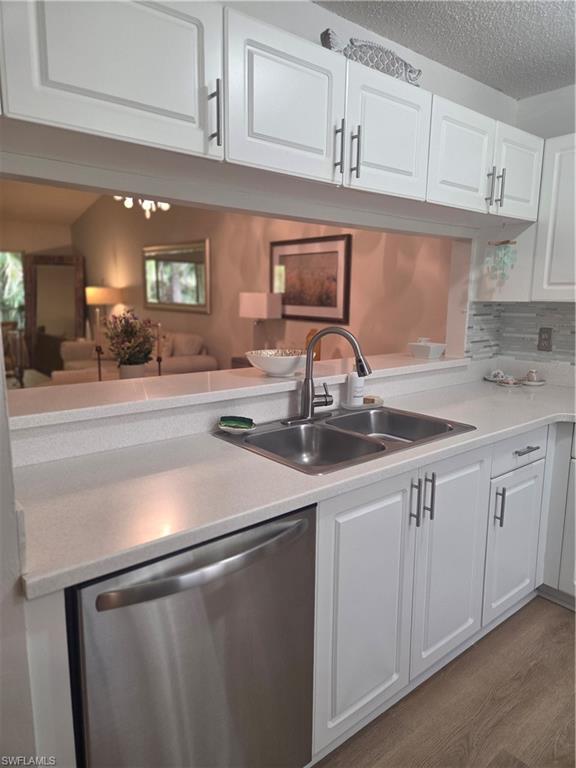 3531 County Barn Road, Unit C201 Naples, FL 34112 - Photo 10 of 20 Kitchen featuring white cabinetry, dishwasher, dark wood-style flooring, a textured ceiling, and decorative backsplash