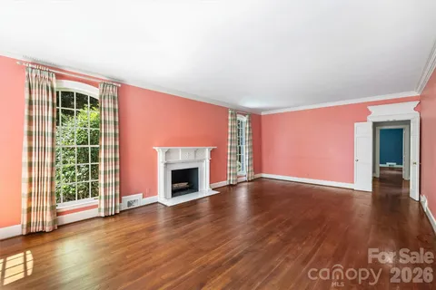 an empty room with wooden floor fireplace and windows