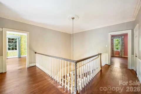a view of a hallway with wooden floor and stairs