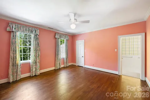 an empty room with wooden floor fan and windows