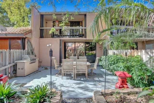 a view of a patio with table and chairs potted plants and large tree