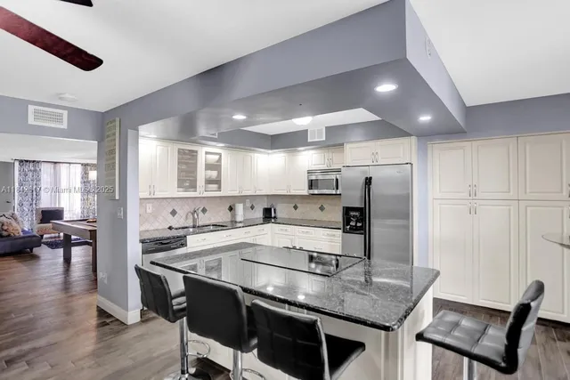 a kitchen with stainless steel appliances granite countertop a table chairs sink refrigerator and microwave