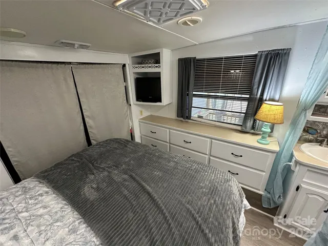 a bedroom with a bed a flat screen tv and dresser