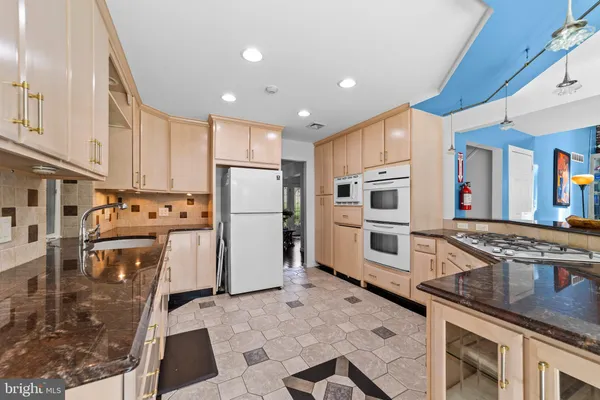 a kitchen with stainless steel appliances granite countertop a refrigerator a stove and a sink