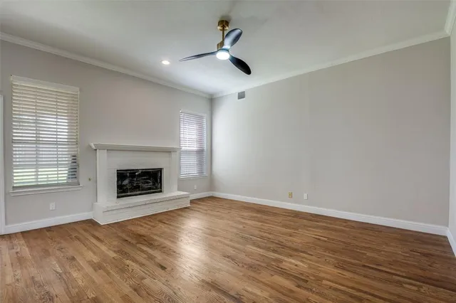 an empty room with windows fireplace and wooden floor