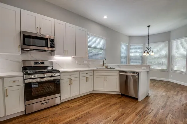 a kitchen with granite countertop white cabinets stainless steel appliances and a sink
