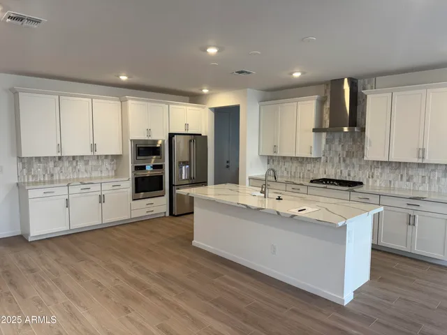 a large kitchen with stainless steel appliances granite countertop a lot of counter space and wooden floors