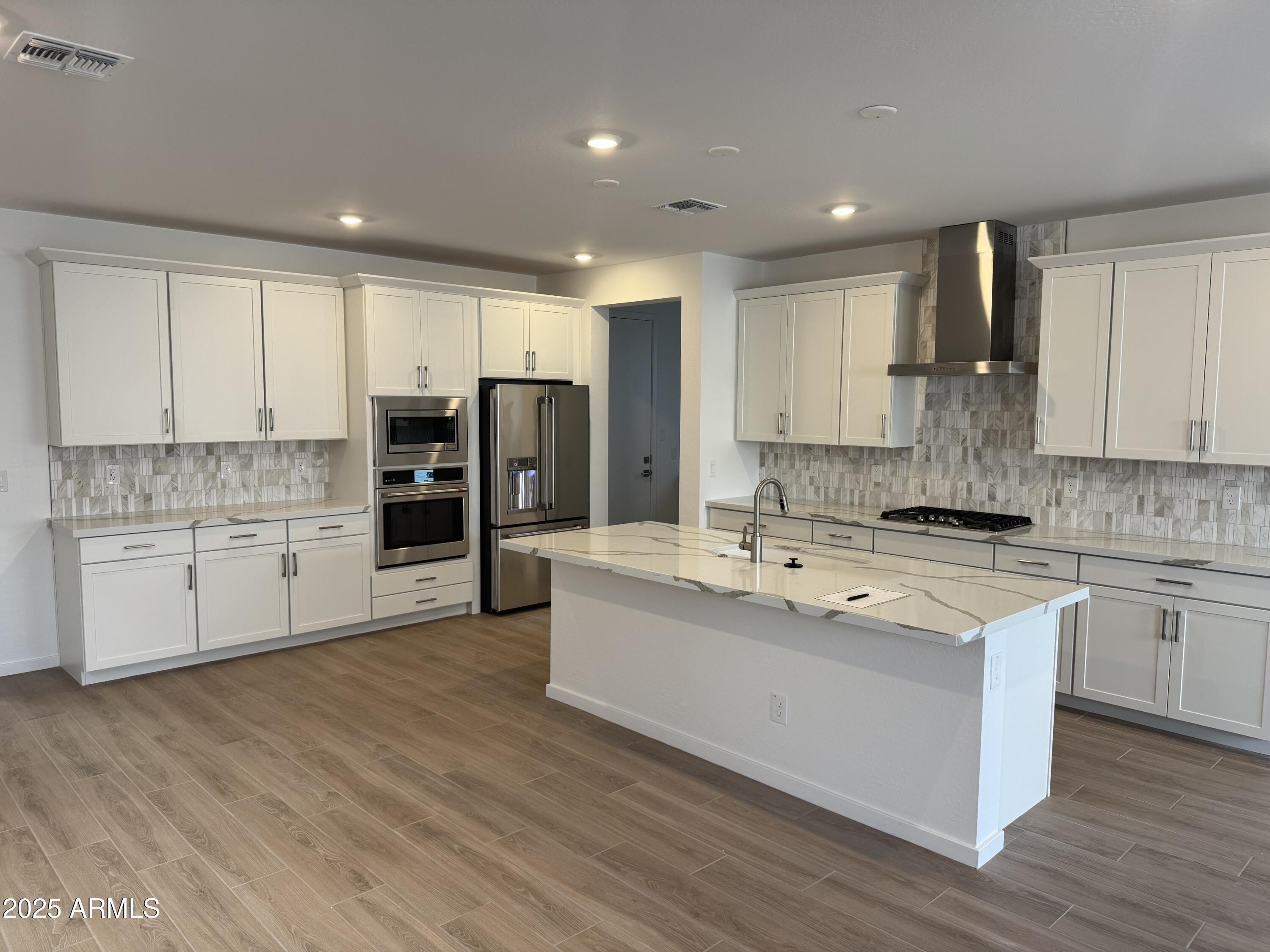 2458 West Maximo Way Phoenix, AZ 85085 - Photo 2 of 22 a large kitchen with stainless steel appliances granite countertop a lot of counter space and wooden floors