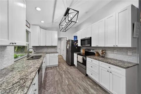 a kitchen with granite countertop a sink a counter space stainless steel appliances and cabinets